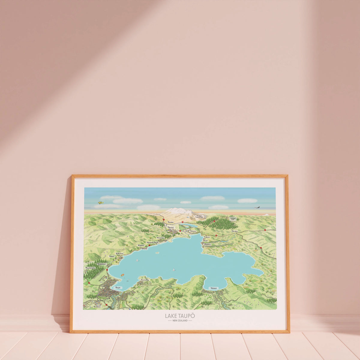 Hand-drawn map art print of Lake Taupō, New Zealand – watercolour land, digital sky and lake, featuring Taupō, Kinloch, Ruapehu, and Ngauruhoe on the horizon. Wood framed version for display.