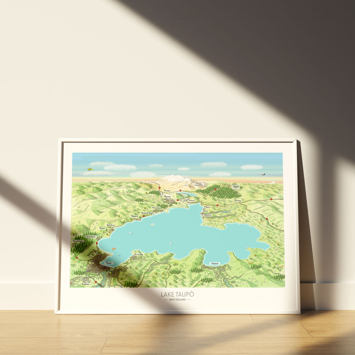 Hand-drawn map art print of Lake Taupō, New Zealand – watercolour land, digital sky and lake, featuring Taupō, Kinloch, Ruapehu, and Ngauruhoe on the horizon. White framed version for display.