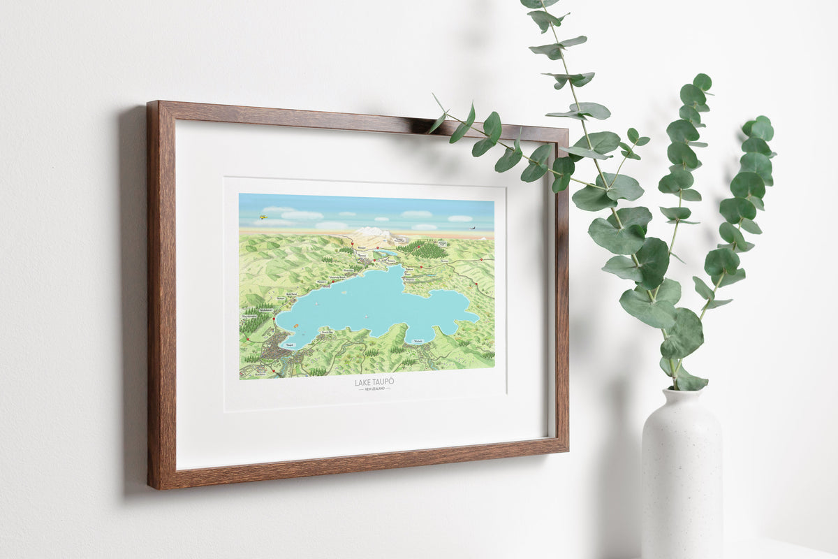 Hand-drawn map art print of Lake Taupō, New Zealand – watercolour land, digital sky and lake, featuring Taupō, Kinloch, Ruapehu, and Ngauruhoe on the horizon. Framed version for display