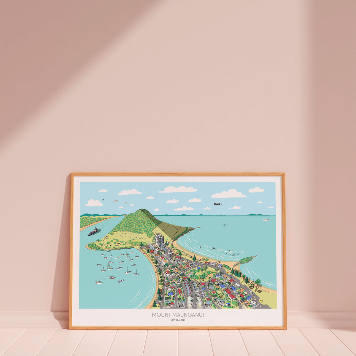 Hand-drawn map art print of Mount Maunganui, New Zealand – watercolour and digital colour, featuring the Mount, beach, harbour, and town layout. Shown in a wood frame for display.