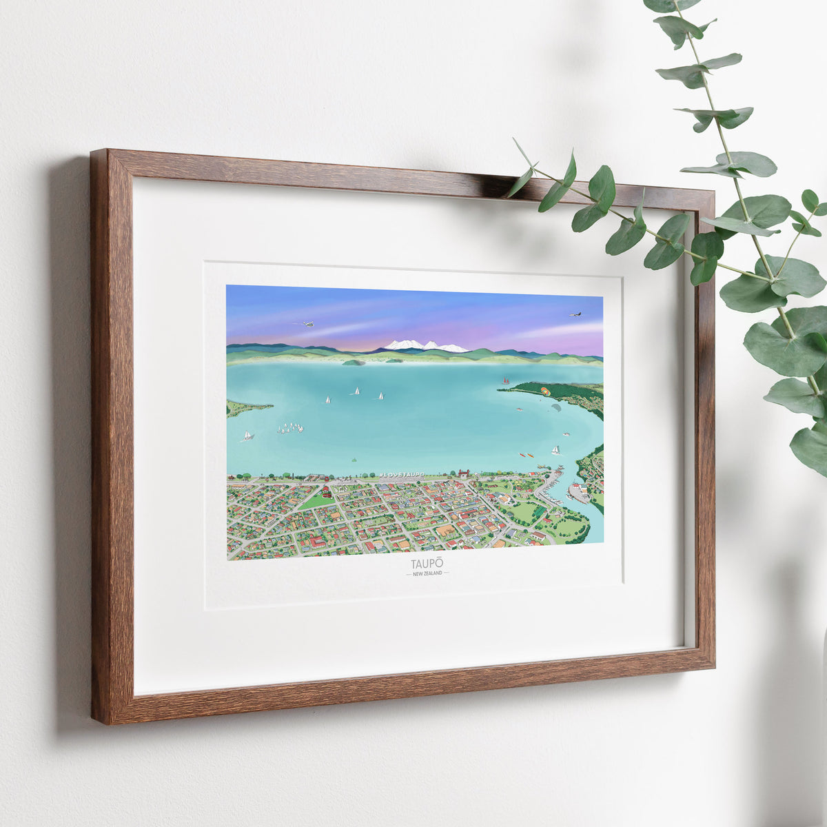 A hand-drawn map of the Taupō area in New Zealand, printed on art museum quality paper, with digital colouring showing the lake, city, and surrounding landscapes, displayed in a dark wood frame