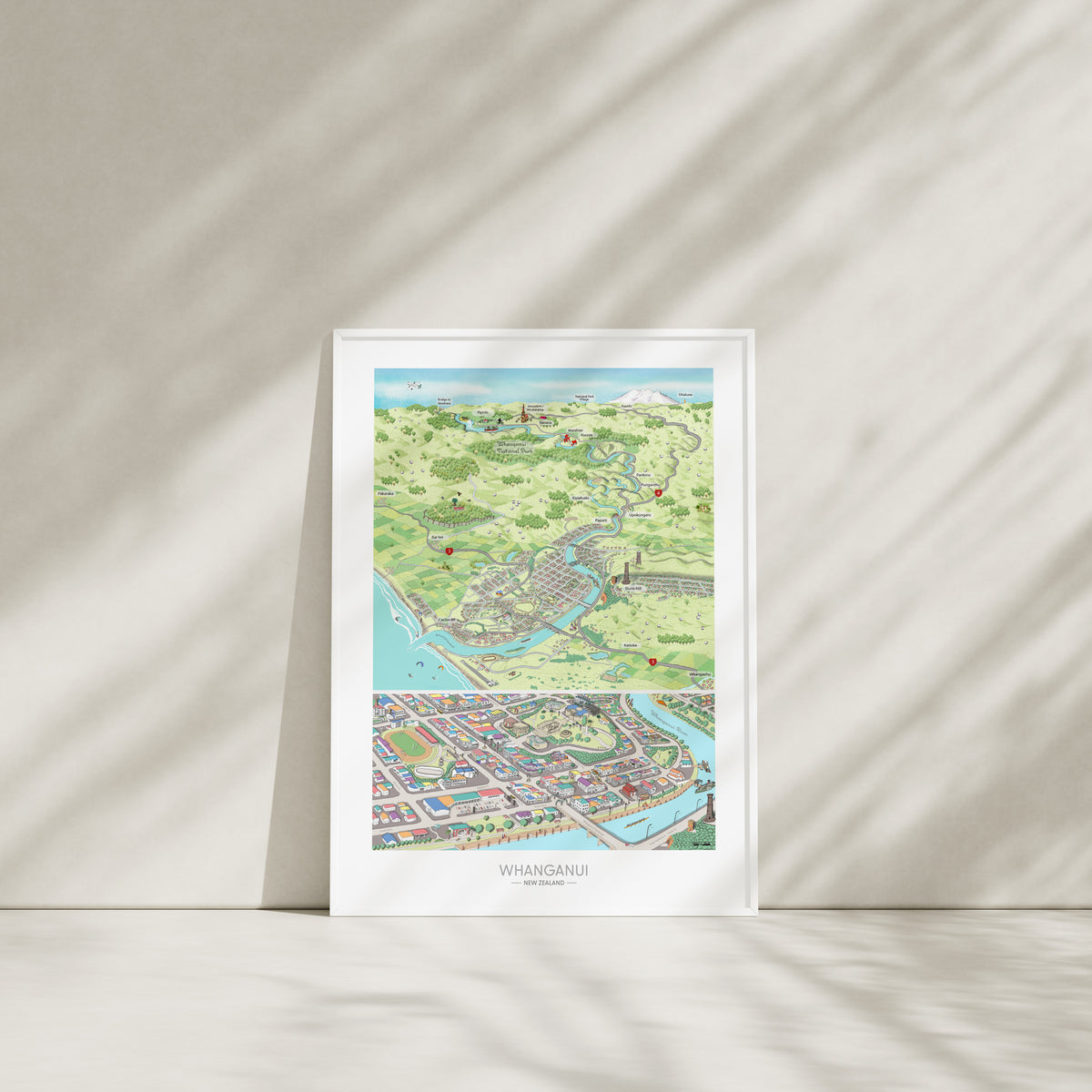 A hand-drawn map of Whanganui art print created in two parts for a District Council project. One part focuses on the city, the other on the wider region of Whanganui, New Zealand. The map highlights the Whanganui River, the Opera House, old houses, the paddle steamer, Durie Hill, the Memorial Tower, and the bridges. White Framed displayed.